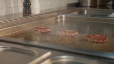 Delicious-burger-patties-cooking-on-hot-stove-in-restaurant-kitchen