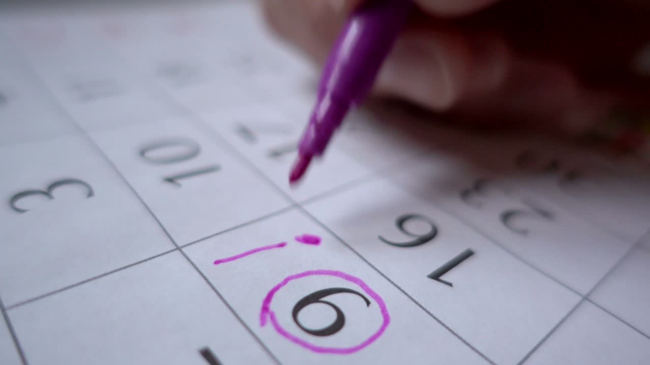 un hombre hace un sello de fecha en el calendario. planear unas vacaciones. cumpleaños. cerca. comercializar la fecha en el calendario, cerca.