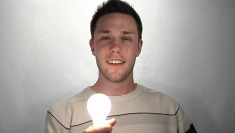 a young man gazes at a compact fluorescent light bulb as it lights 1