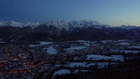 Dusk-Over-Illuminated-Zakopane-Town-During-Winter-In-Poland---aerial-drone-shot