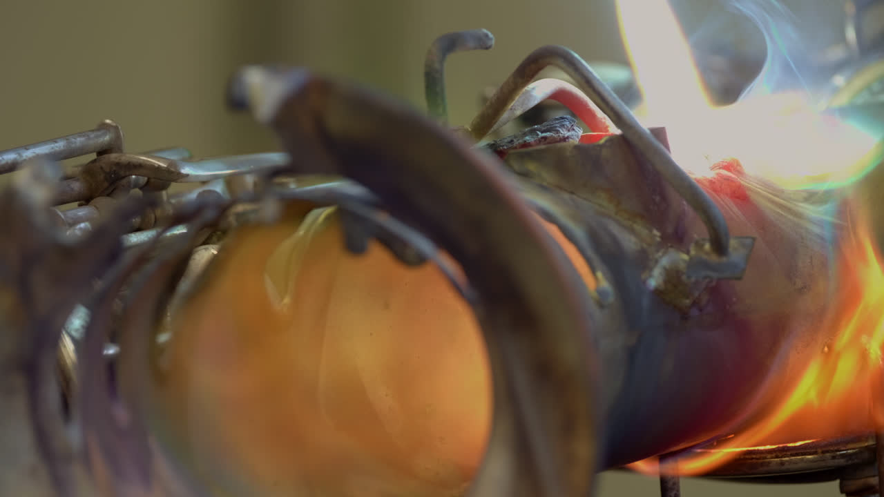 un herrero usa soldadura de gas para derretir un saxofón de latón, lo que genera chispas destructivas y llamas de colores brillantes