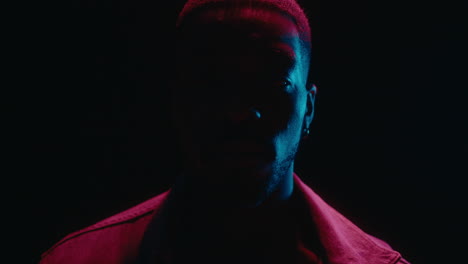 neon light portrait of black man in dark studio