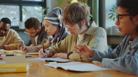 multi-ethnic students writing in copybooks during exam or lecture