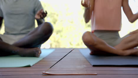 meditating on yoga mats, diverse couple practicing mindfulness with incense burning