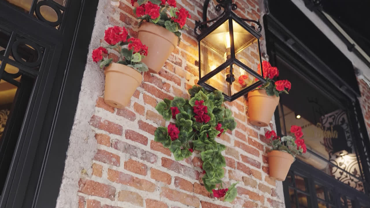 Beautiful slow motion close-up shot of a flower decoration in pots hanging and farol in a restaurant in front of the Las Ventas bullring in Madrid.