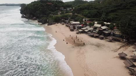 Vista-Aérea,-Que-Muestra-A-Los-Turistas-Jugando-Fútbol-De-Playa-En-La-Playa-De-Watu-Lawang,-Gunung-Kidul,-Yogyakarta,-Indonesia