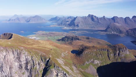 Vista-Aérea-De-Una-Hermosa-Cadena-De-Montañas-Y-Fiordos-En-Un-Hermoso-Día-De-Pájaro-Azul-En-Las-Islas-Lofoten,-Noruega,-Cerca-De-La-Playa-De-Kvalvika