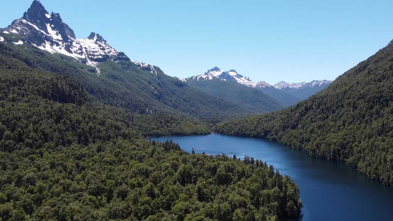 Drone footage of beatuful lake surraunded by snowy mountains and blooming green forest at Patagonia argentina