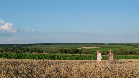 mom and teenage daughter walking through a picturesque wheat field