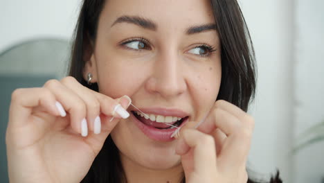 mujer lavándose los dientes con hilo dental