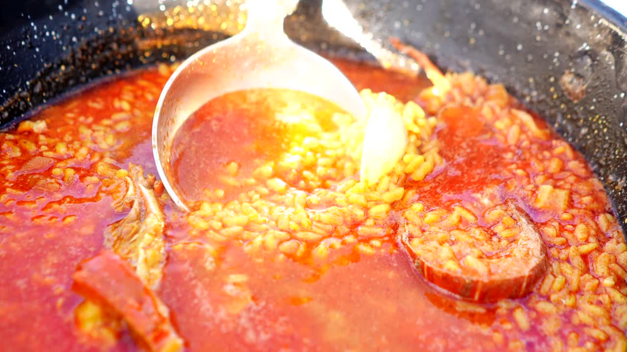 ladle scooping soupy seafood rice with lobster