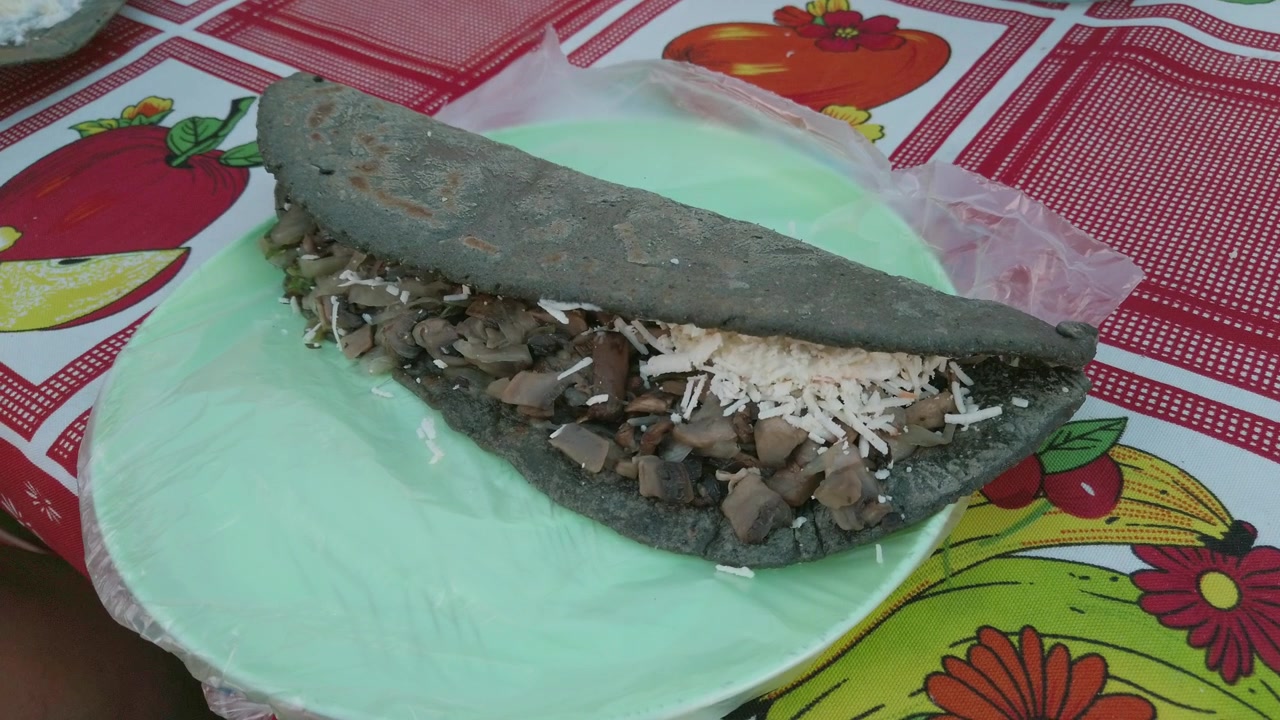 Blue corn quesadilla filled with mushrooms and shredded cheese served on plate at traditional food stall during local market in Mexico