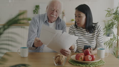 elderly man and young woman discussing documents at home