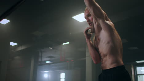 A-male-athlete-lifts-a-weight-bar-with-one-hand-in-slow-motion.-Strength-training-for-a-boxer.-The-man-is-sweating-working-out-in-the-gym-practicing-the-force-of-the-blow-with-his-hand