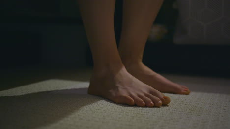 close up of a woman's feet as she slowly gets out of bed and walks out of frame