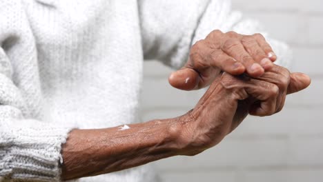 applying lotion to elderly person's hands and arms