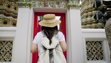 cheerful young asian woman traveling at wat pho temple in bangkok, thailand.