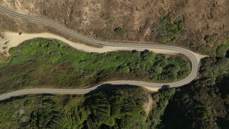 Lowering-top-down-drone-shot-of-a-winding-part-of-the-Pacific-Coast-Highway-in-California