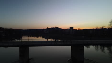 Excursionista-Caminando-Por-Un-Puente-Sobre-Un-Río-Al-Atardecer-En-Passau-Alemania