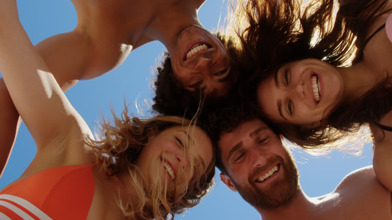Jovens amigos formando um círculo na praia 4K
