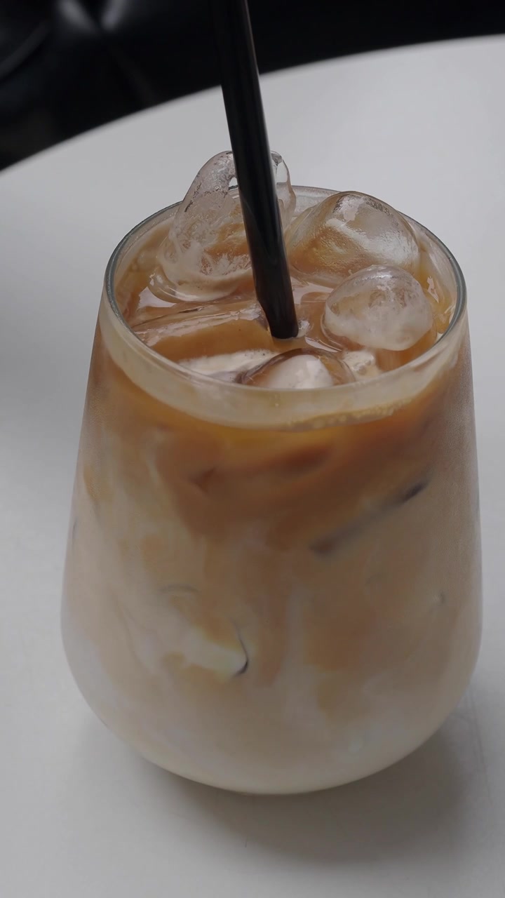 Inserimento di una cannuccia in un rinfrescante latte macchiato freddo