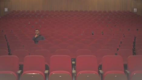 a tall white guy enters in an empty theatre. he takes a sit and he is the only one watching the show. he starts to see and enjoy the show that he sees on stage