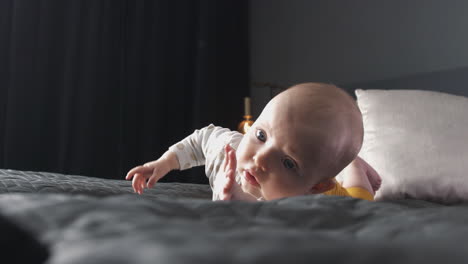 baby-girl-on-big-bed-learning-to-roll-over-and-reaching-for-feet