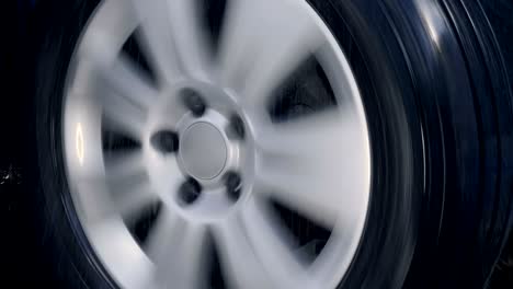 car wheel with shiny silver rim rides in the rain drops