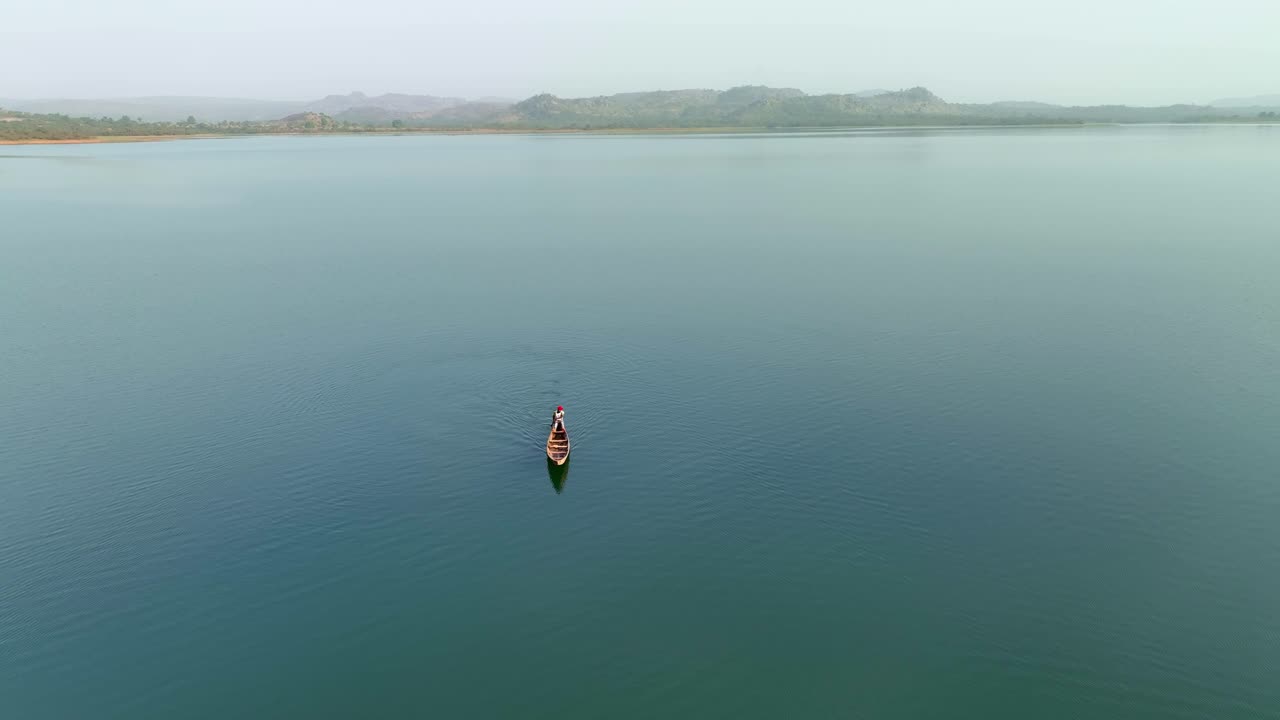 Aerial - Wide shot of a man rowing a canoe on a crater lake
