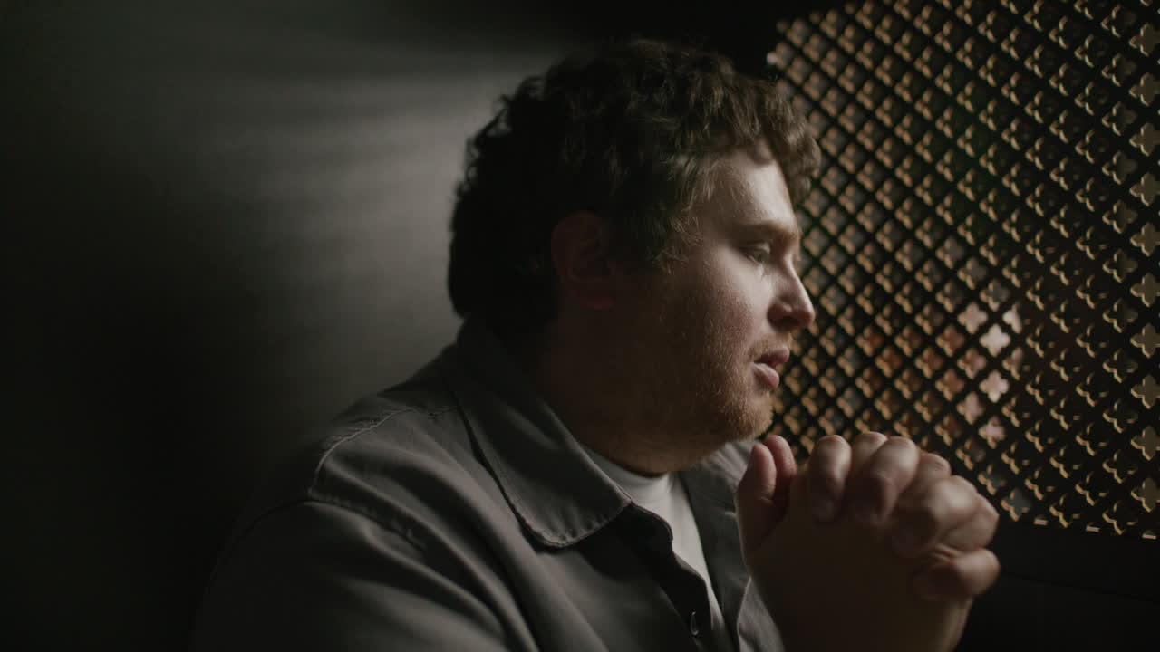 Young Man Praying near Ornate Screen during Spiritual Confession