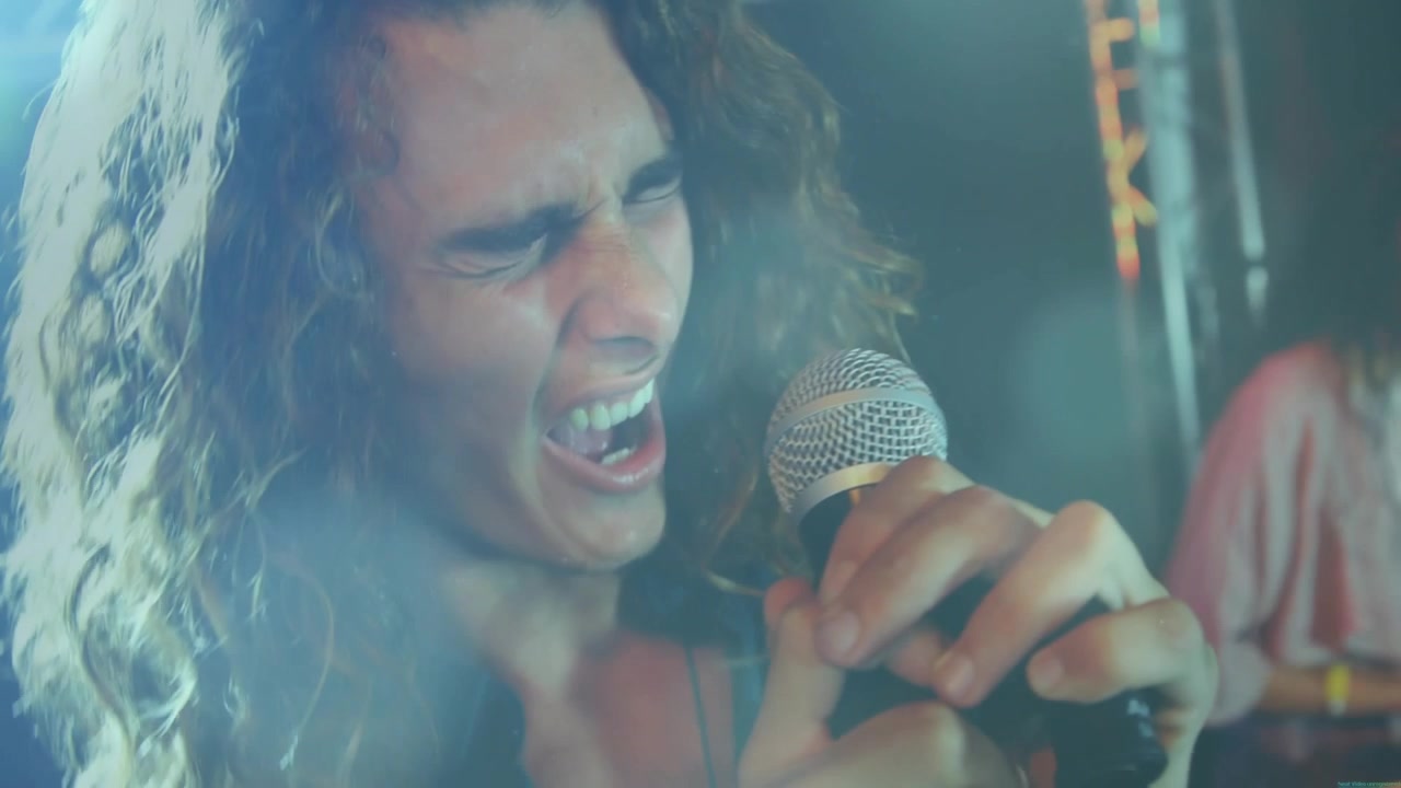 Cantante solista che stringe il microfono, canta a squarciagola e proietta la voce, girandosi verso i coristi mentre le luci del palco si accendono e spengono.
