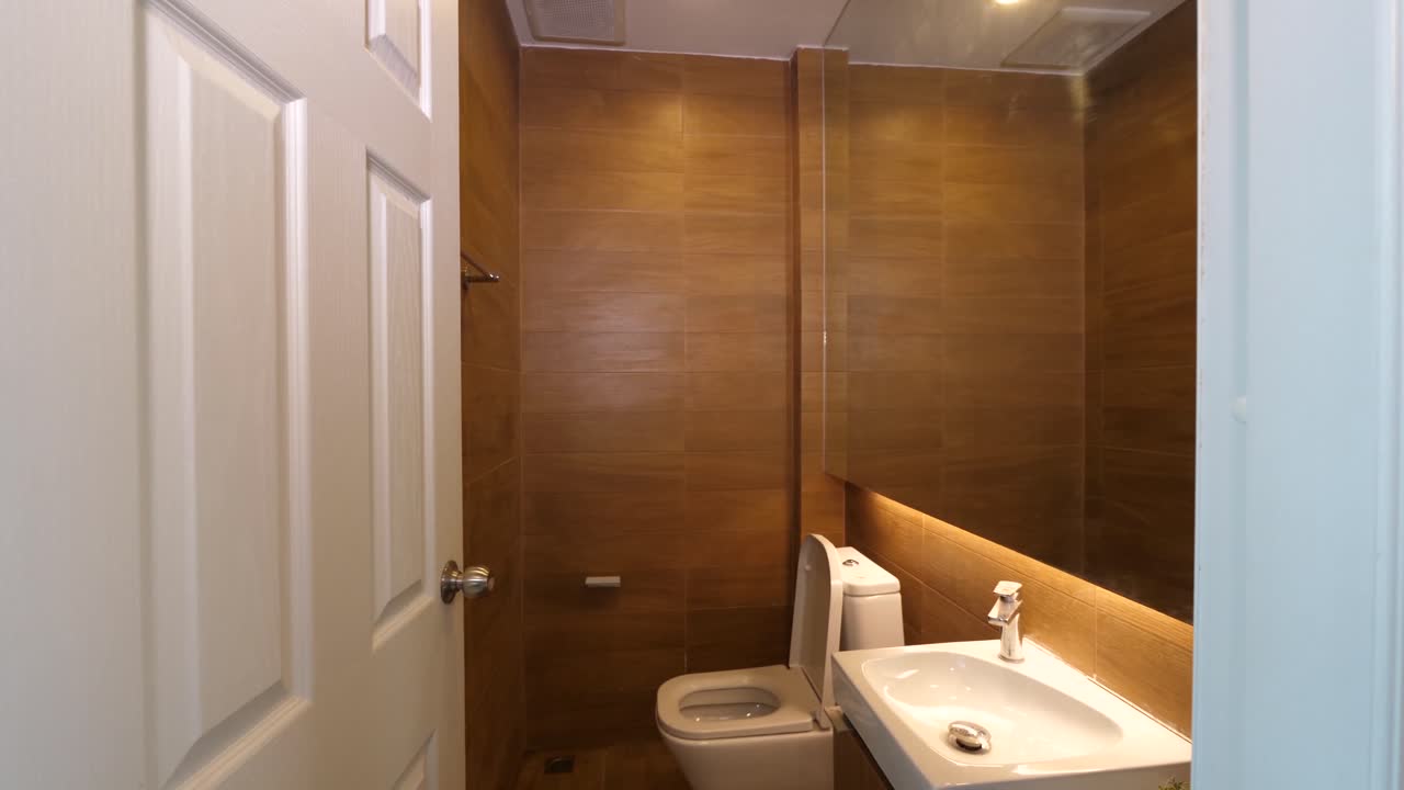 Clean Toilet With Washbasin Decorated With Brown Wall Tiles
