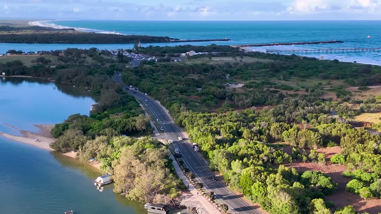 Aerial view of a scenic road winding through lush greenery alongside a tranquil waterway.