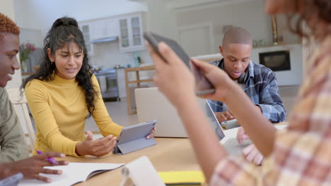 Fröhliche,-Vielfältige-Gruppe-Von-Teenager-Freunden,-Die-Zu-Hause-Mit-Tablets-Am-Tisch-Lernen,-Zeitlupe