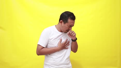 asian adult man coughing on yellow background