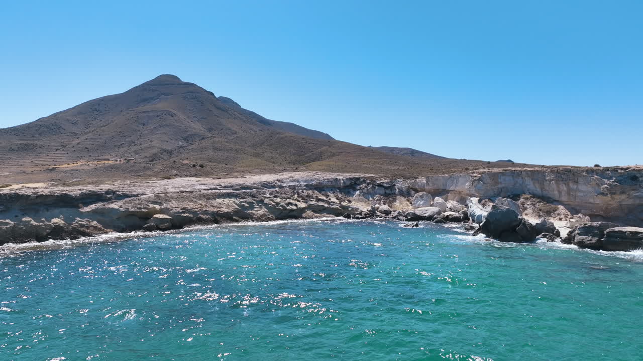 Low fast flight above dramatic white stone sea wall under Los Frailes volcano