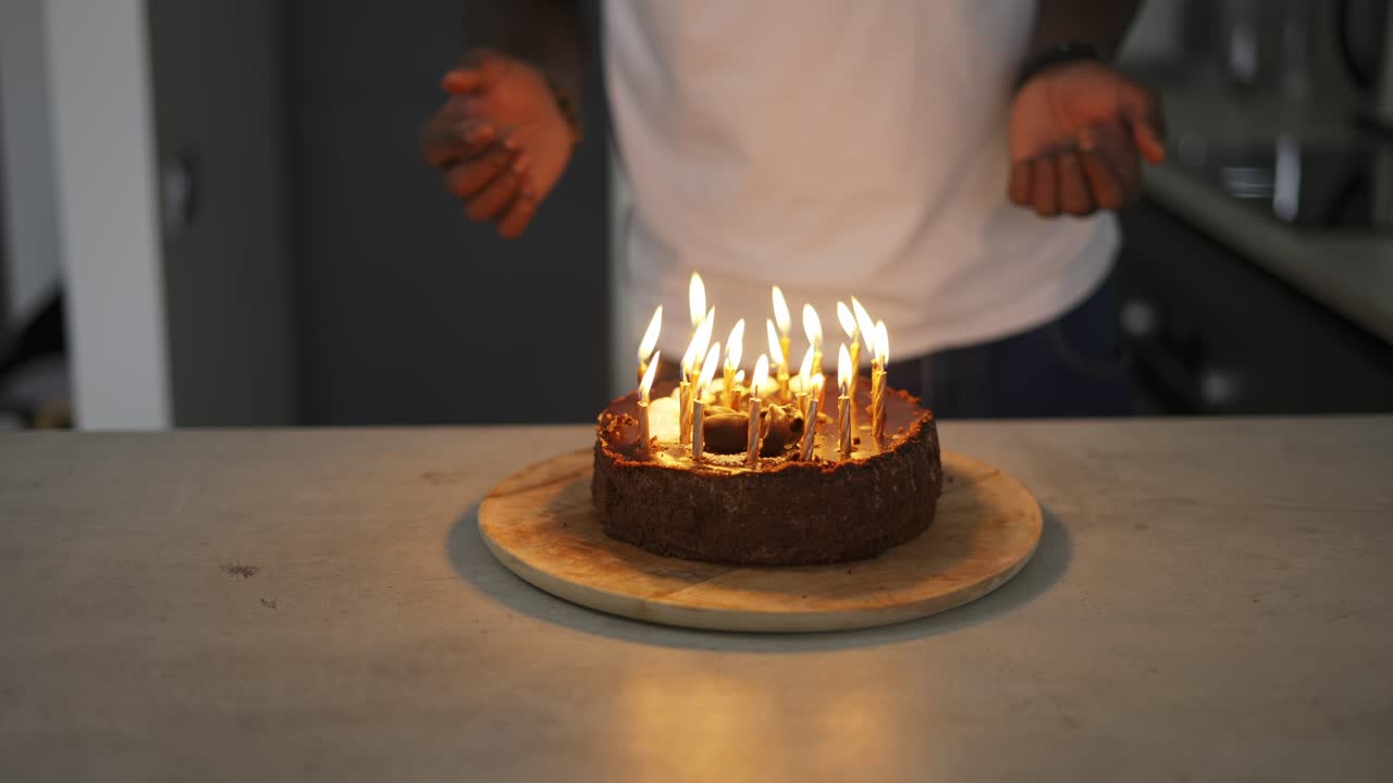 hombre negro irreconocible encendiendo velas en el pastel de cumpleaños en el anochecer