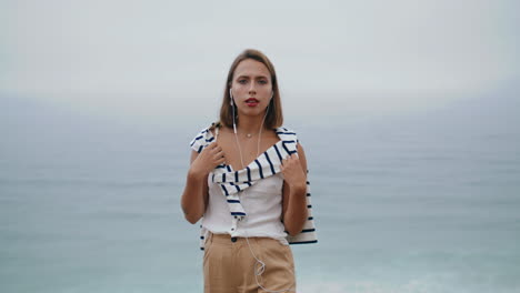 smiling millennial listening music at ocean view closeup. relaxed girl posing