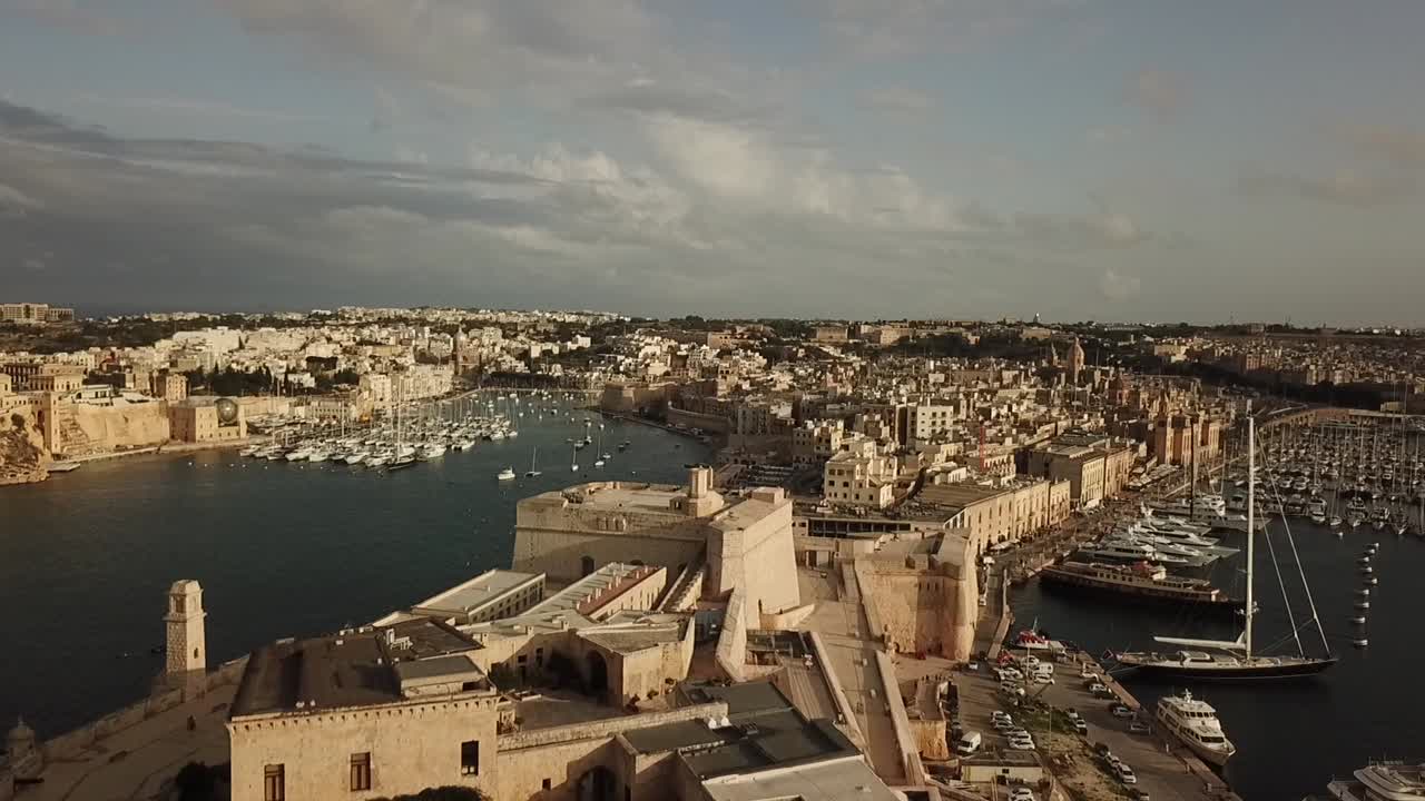 Aerial view of fort St. Angelo in the grand harbour of Malta, Europe. Dolly shot pulling away from the fort, revealing the chapel and flags.