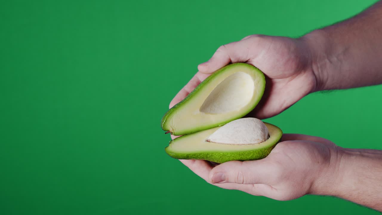 Opening fresh halved avocado .