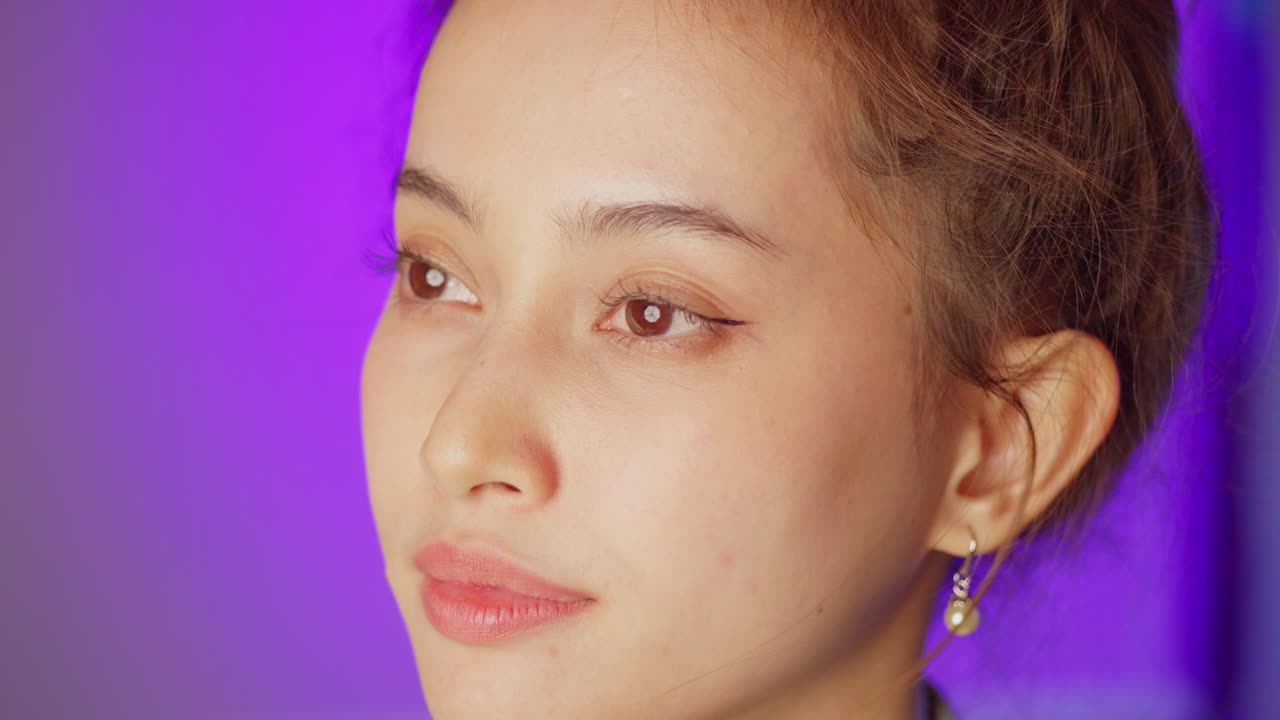 A female model opens her eyes, looks straight ahead to the left side of the frame, turns to the right center, and smiles.