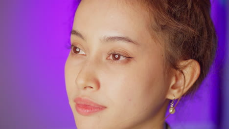 a female model opens her eyes, looks straight ahead to the left side of the frame, turns to the right center, and smiles.