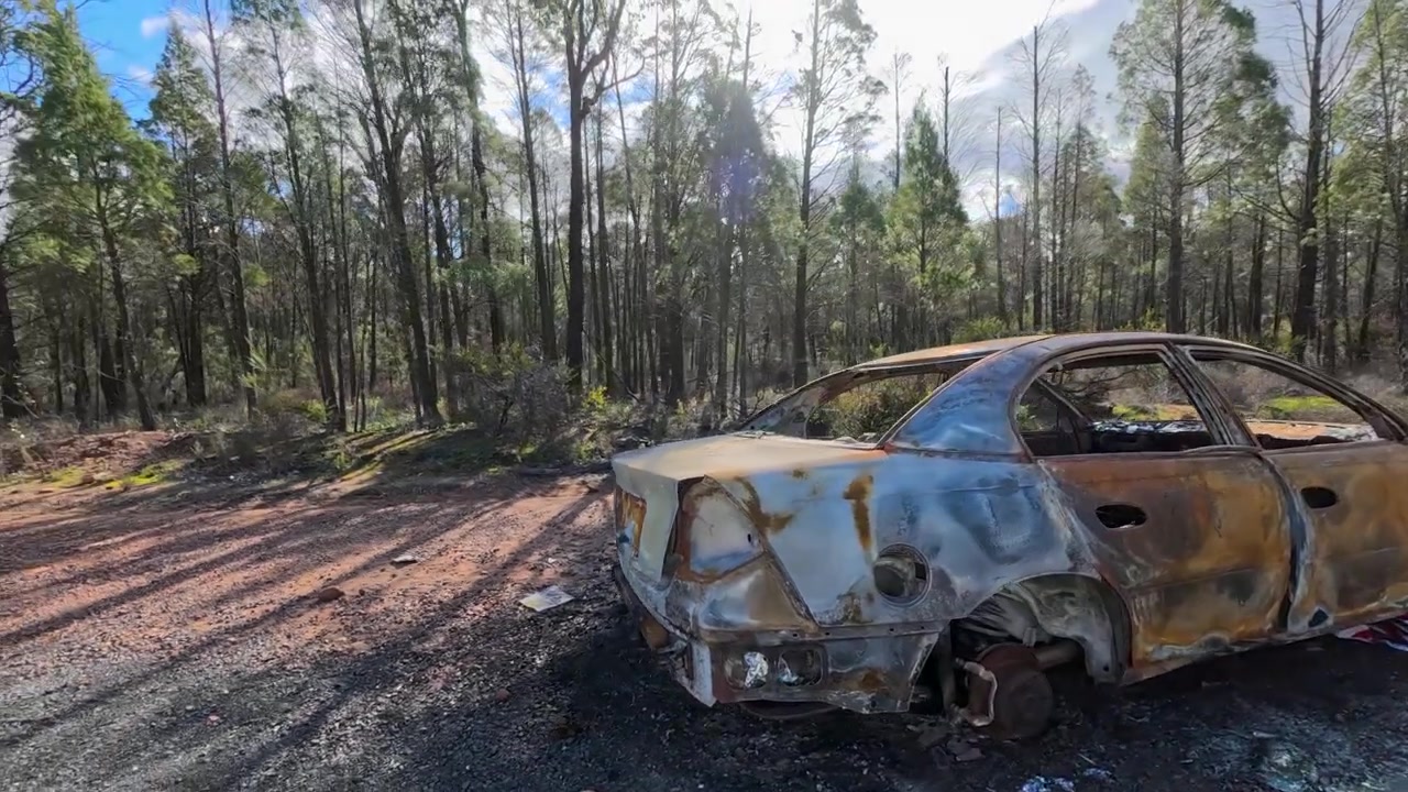 La telecamera si muove intorno a una berlina arrugginita e danneggiata dal fuoco abbandonata nella foresta di Pilliga, Australia.