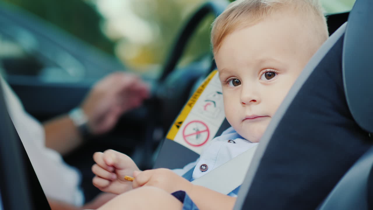 A Little Boy Is Sitting In A Car Seat Near His Father Smiling Happily Concept - Safety And Care Slow