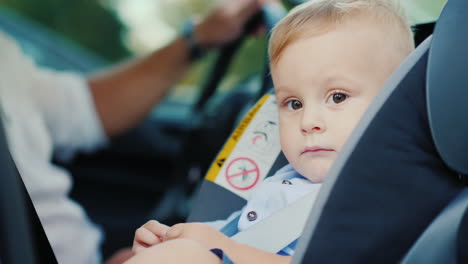 Ein-Kleiner-Junge-Sitzt-In-Einem-Autositz-In-Der-Nähe-Seines-Vaters-Und-Lächelt-Glücklich-Konzept---Sicherheit-Und-Pflege-Langsam