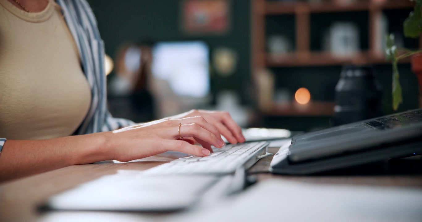 Donna che digita su una tastiera wireless alla scrivania in un ufficio domestico