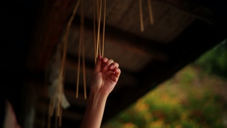 Hand touching hanging wooden sticks