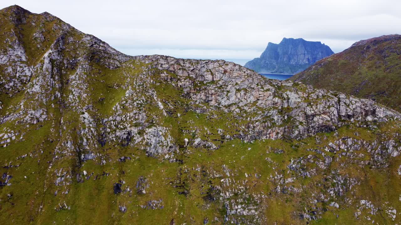 imágenes aéreas volando hacia una montaña empinada en las islas lofoten del norte de noruega con excursionistas aventureros subiendo para ver una hermosa vista en la cima