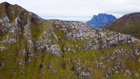 Aerial-footage-flying-towards-steep-mountain-in-northern-Norway's-Lofoten-islands-with-adventurous-hikers-climbing-up-to-see-beautiful-view-at-the-top