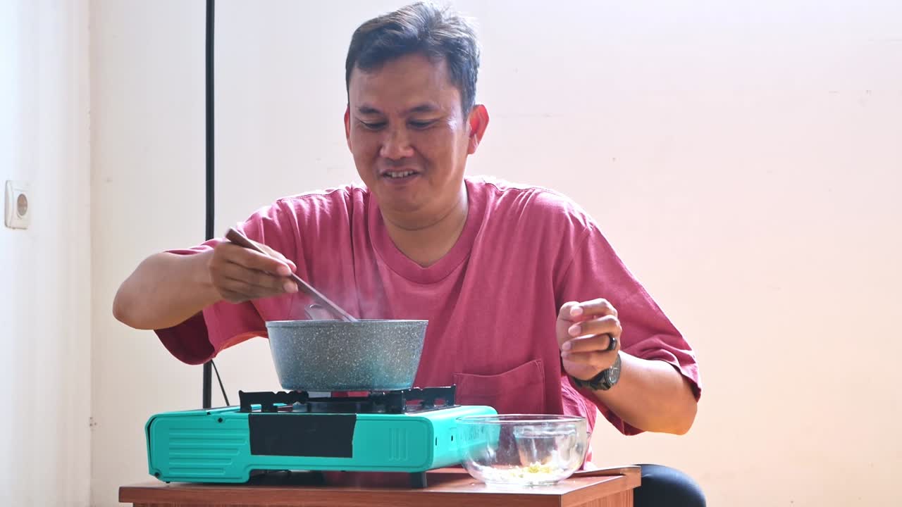 Asian Man intensely sniffed steaming soup from pot on portable stove